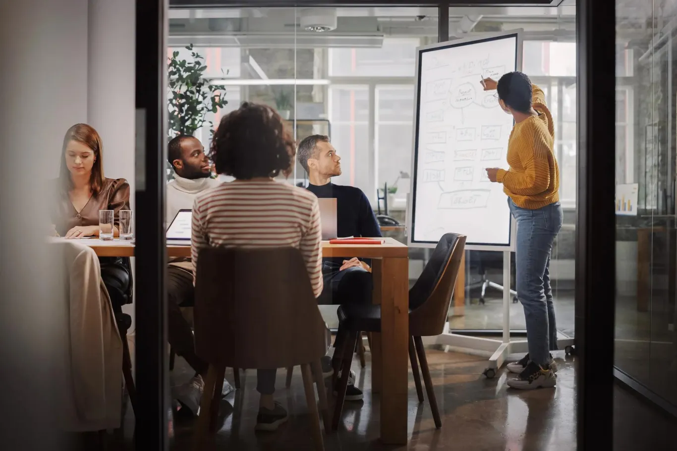 A group of coworkers in a meeting reviewing something on a large screen.